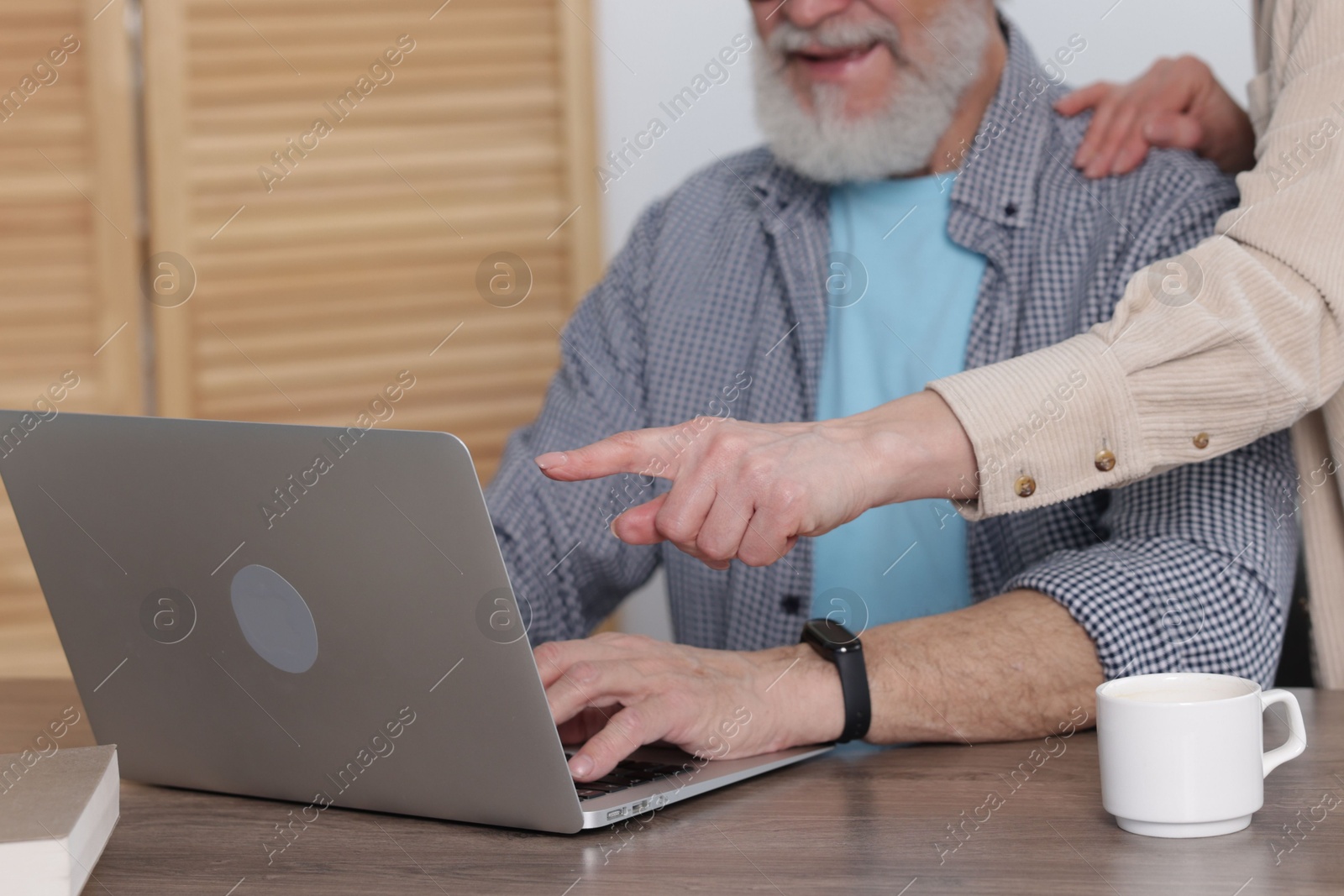 Photo of Senior man and mature woman watching something on laptop at home. Happy couple