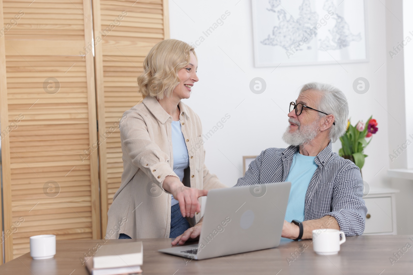 Photo of Senior man and mature woman with laptop at home. Happy couple