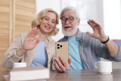 Photo of Senior man and mature woman having video chat via smartphone at home, selective focus. Happy couple