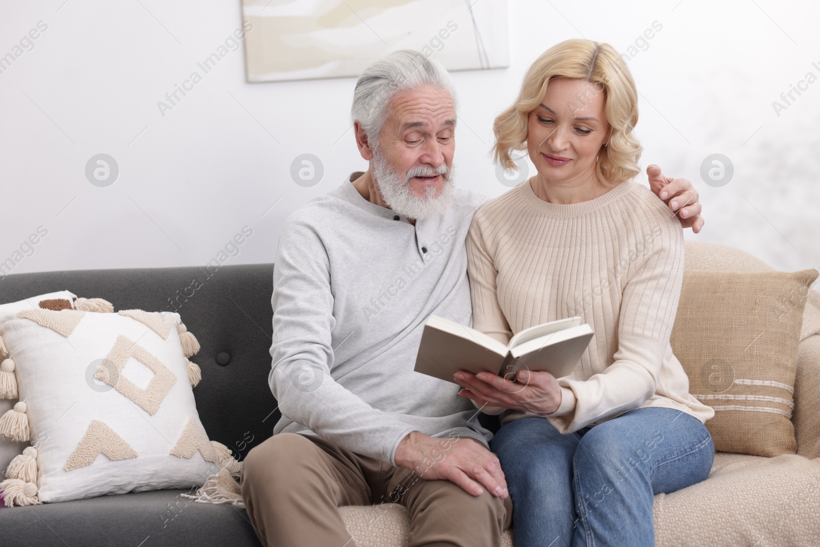 Photo of Senior man and mature woman reading book at home. Happy couple