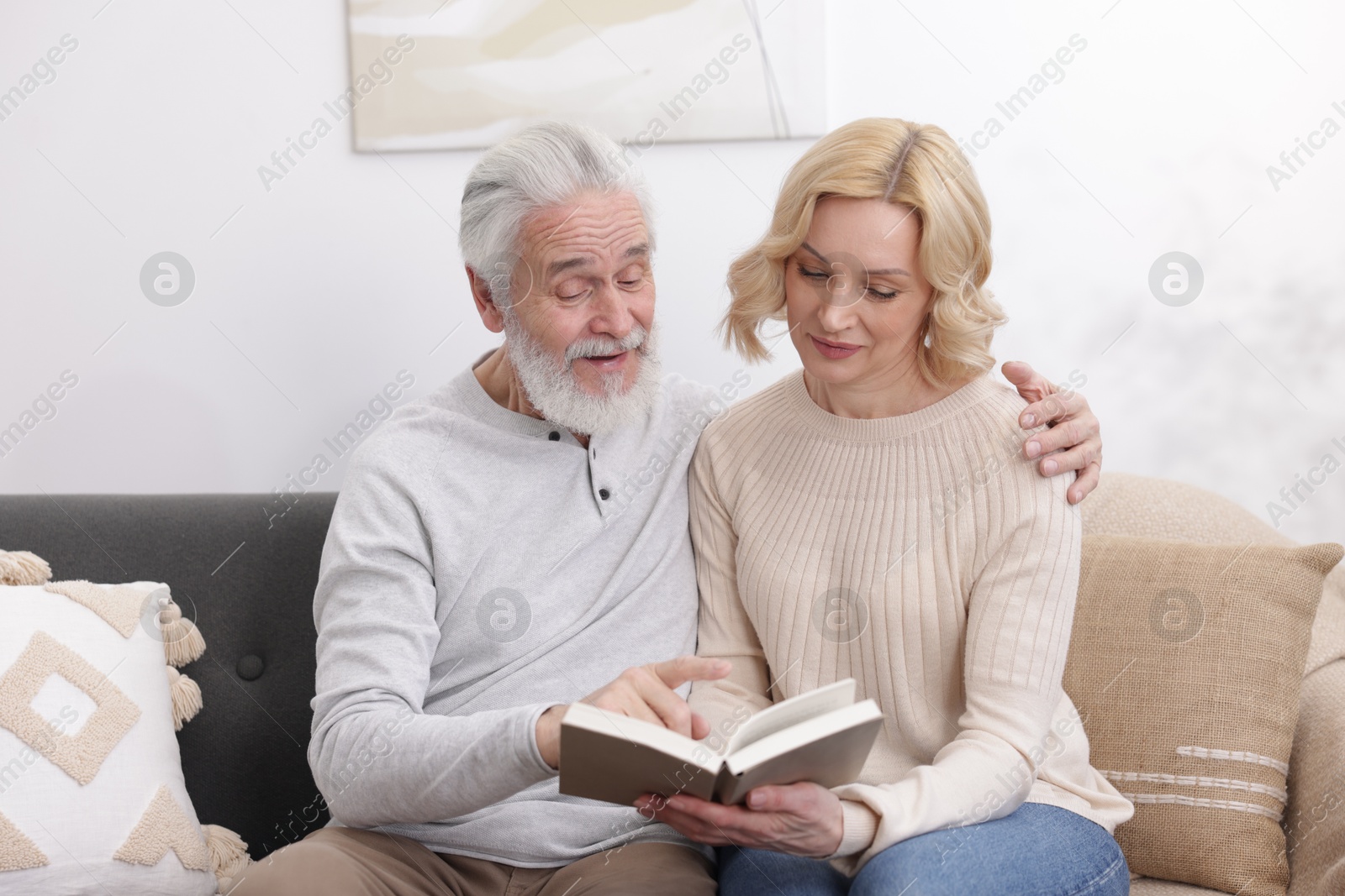 Photo of Senior man and mature woman reading book at home. Happy couple