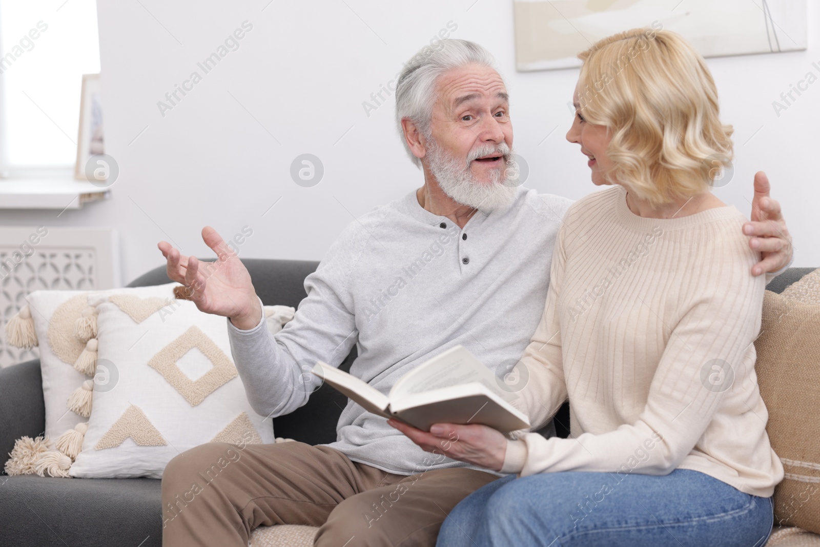 Photo of Senior man and mature woman with book spending time together at home. Happy couple