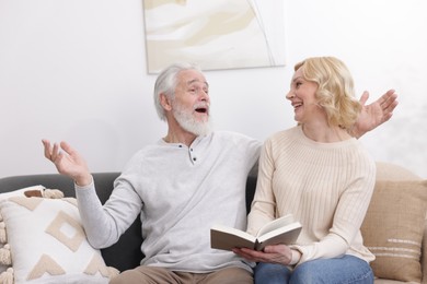 Photo of Senior man and mature woman with book spending time together at home. Happy couple