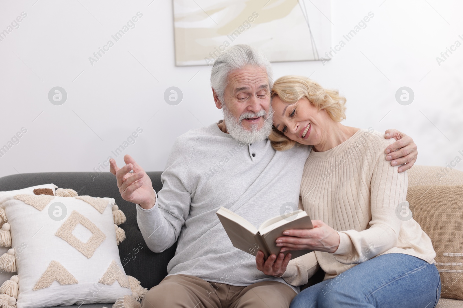 Photo of Senior man and mature woman reading book at home. Happy couple