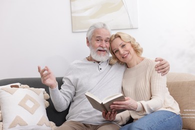 Senior man and mature woman with book spending time together at home. Happy couple