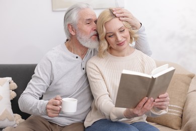 Senior man and mature woman with book spending time together at home. Happy couple