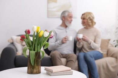 Senior man and mature woman with coffee spending time together at home, selective focus. Happy couple