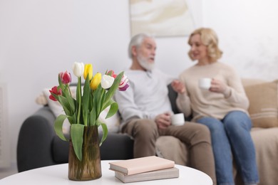 Senior man and mature woman with coffee spending time together at home, selective focus. Happy couple