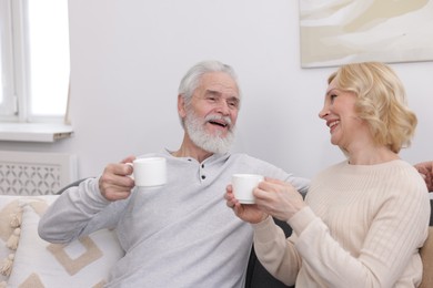 Photo of Senior man and mature woman with coffee spending time together at home. Happy couple