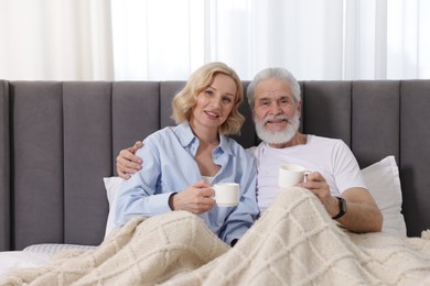 Photo of Senior man and mature woman with coffee spending time together at home. Happy couple