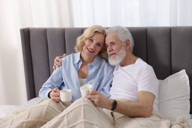 Senior man and mature woman with coffee spending time together at home. Happy couple