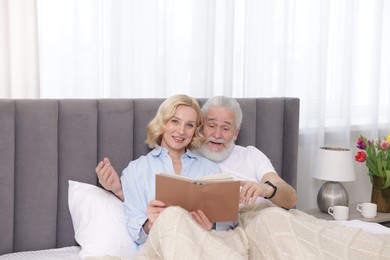 Photo of Senior man and mature woman with book spending time together at home. Happy couple