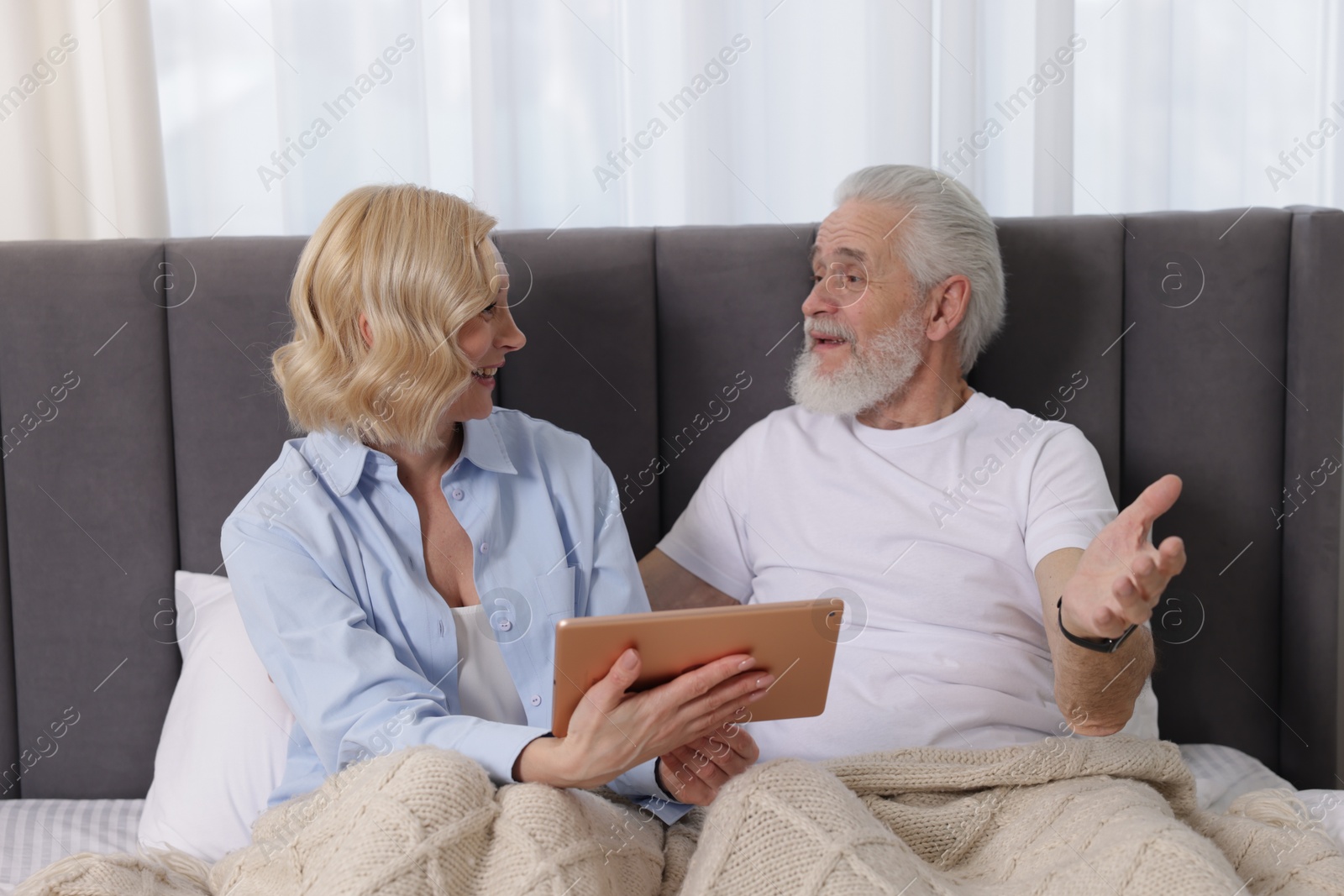 Photo of Senior man and mature woman with tablet spending time together at home. Happy couple