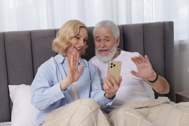 Senior man and mature woman having video chat via smartphone at home. Happy couple