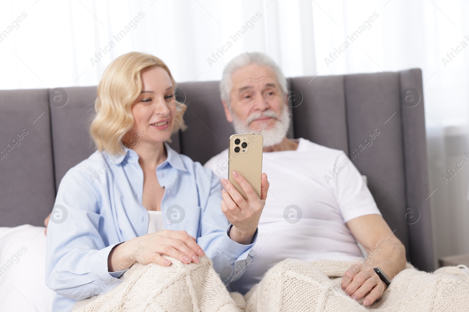 Photo of Senior man and mature woman with smartphone at home, selective focus. Happy couple