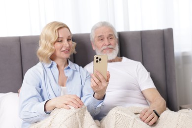 Photo of Senior man and mature woman with smartphone at home, selective focus. Happy couple