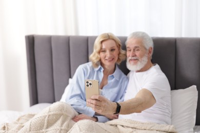 Photo of Senior man and mature woman watching something on smartphone at home, selective focus. Happy couple