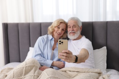 Photo of Senior man and mature woman watching something on smartphone at home, selective focus. Happy couple