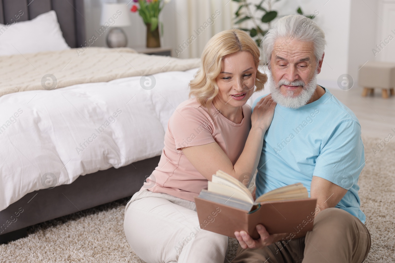 Photo of Senior man and mature woman reading book at home. Happy couple