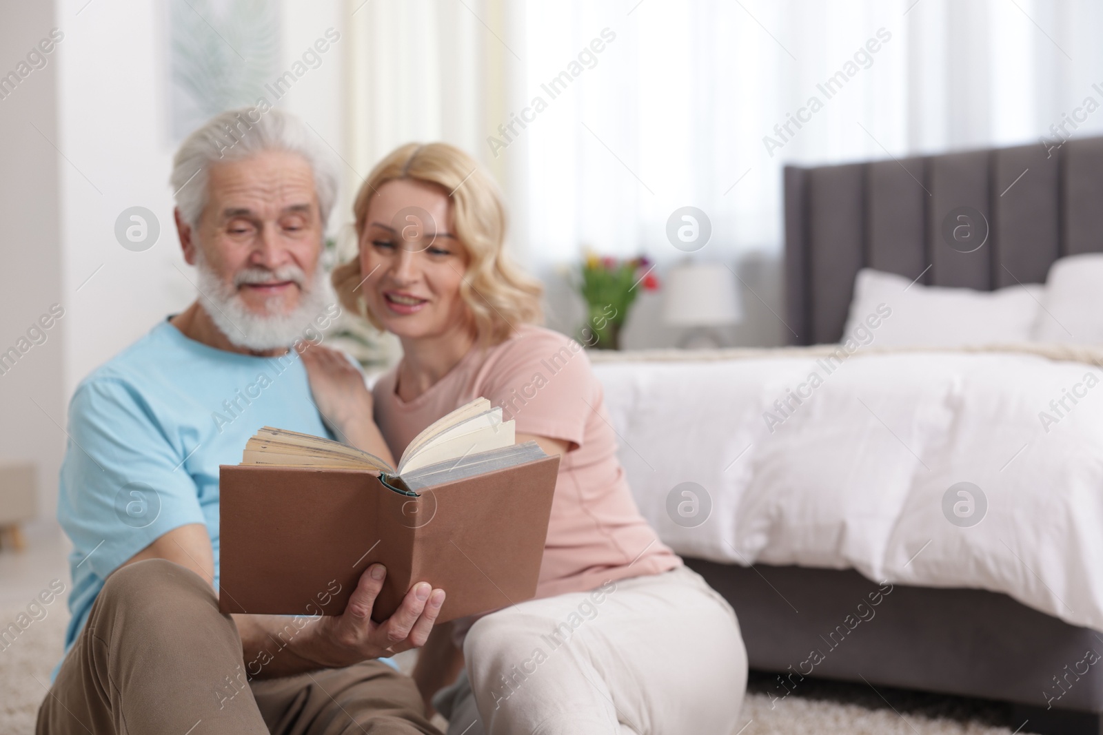 Photo of Senior man and mature woman reading book at home. Happy couple