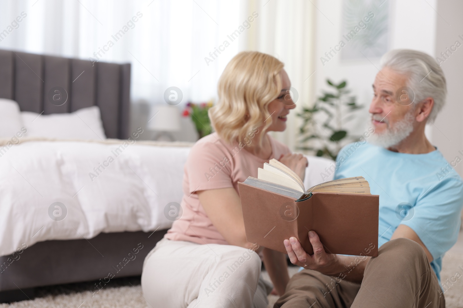 Photo of Senior man and mature woman reading book at home. Happy couple