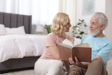 Senior man and mature woman reading book at home. Happy couple