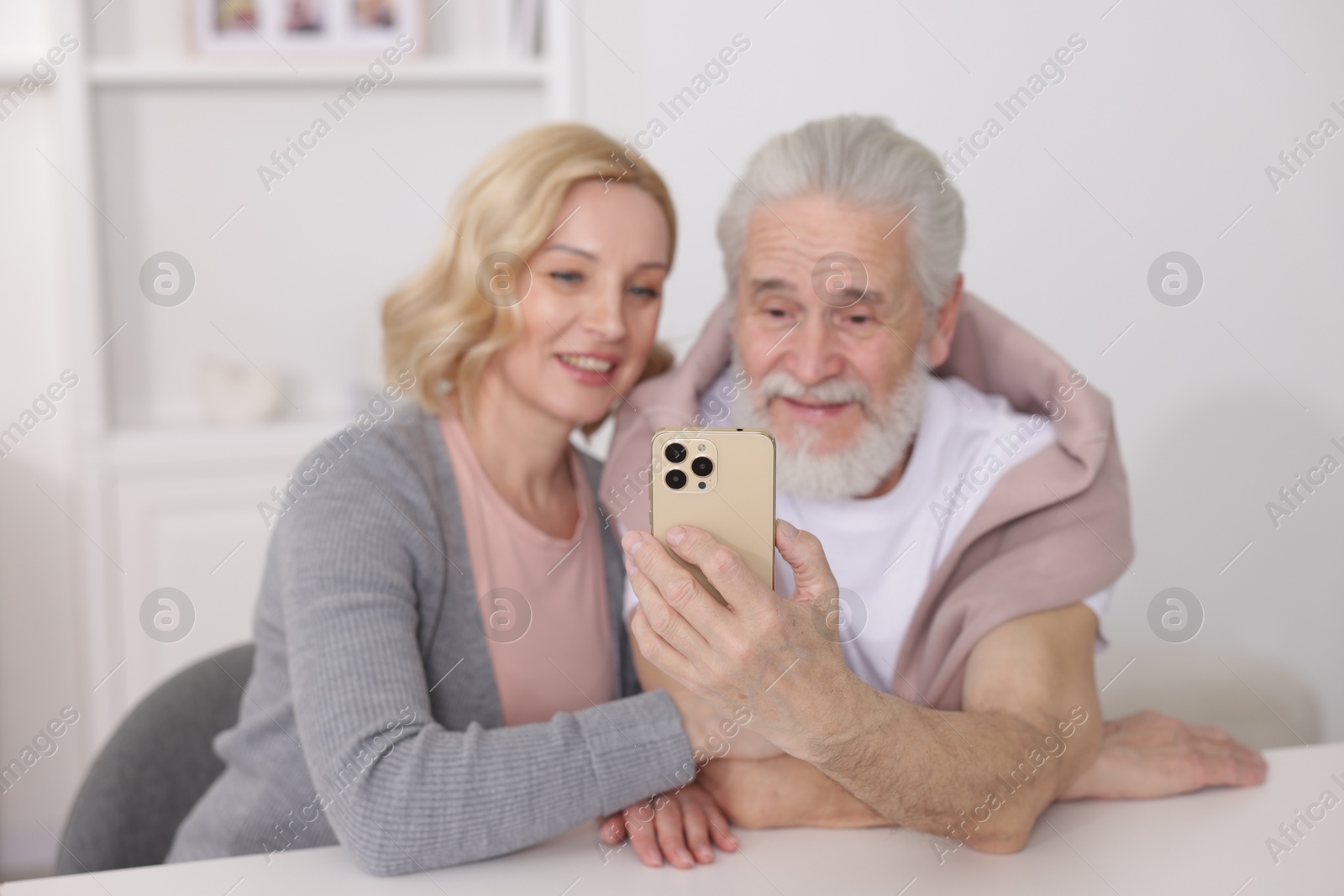 Photo of Senior man and mature woman watching something on smartphone at home, selective focus. Happy couple