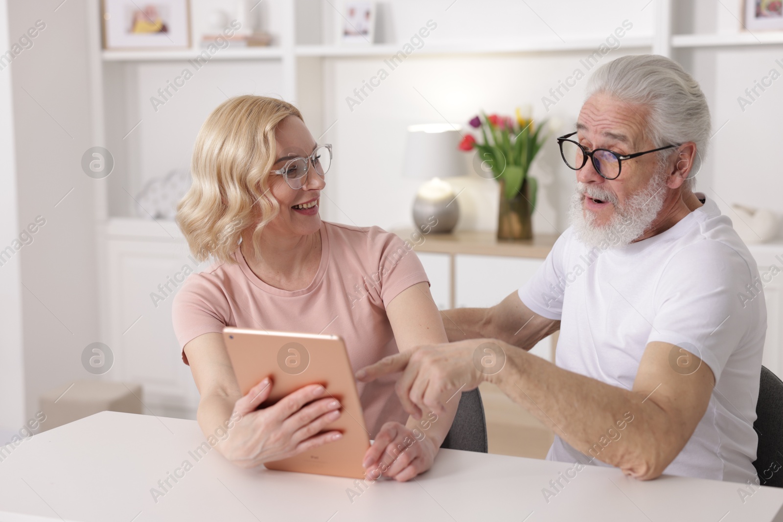 Photo of Senior man and mature woman with tablet spending time together at home. Happy couple