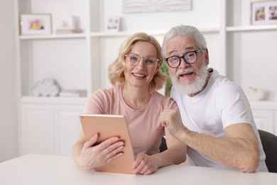 Senior man and mature woman with tablet spending time together at home. Happy couple