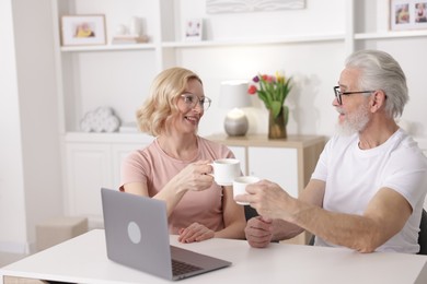 Senior man and mature woman with coffee spending time together at home. Happy couple