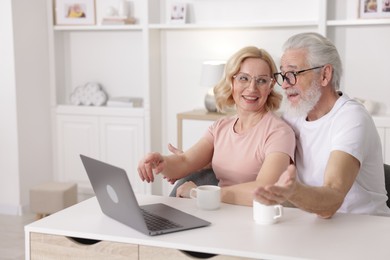 Photo of Senior man and mature woman with laptop spending time together at home. Happy couple