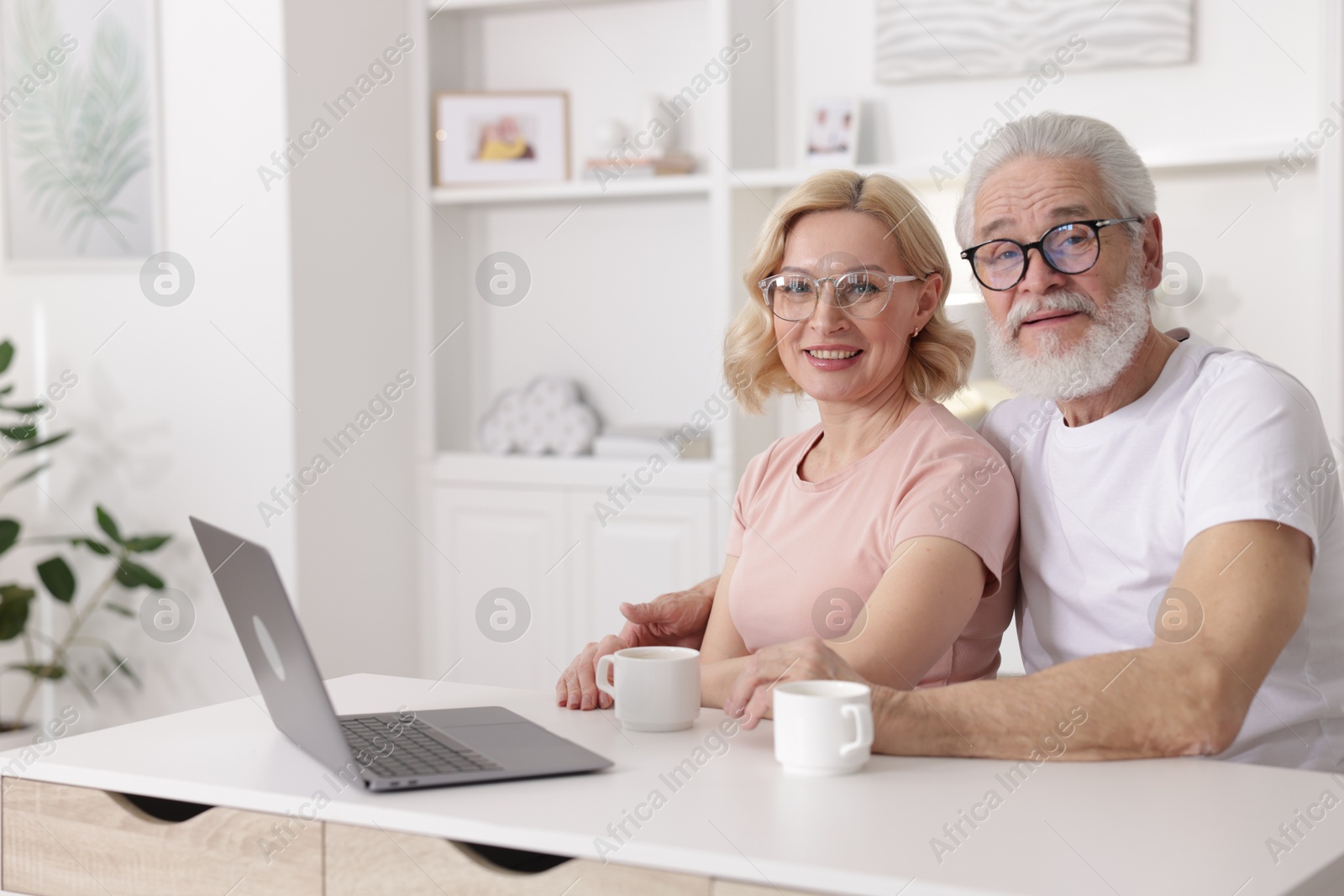 Photo of Senior man and mature woman with laptop spending time together at home. Happy couple