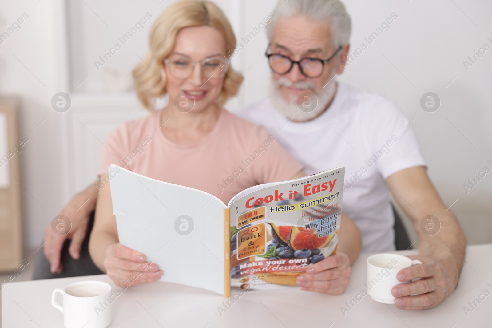 Photo of Senior man and mature woman reading magazine at home, selective focus. Happy couple