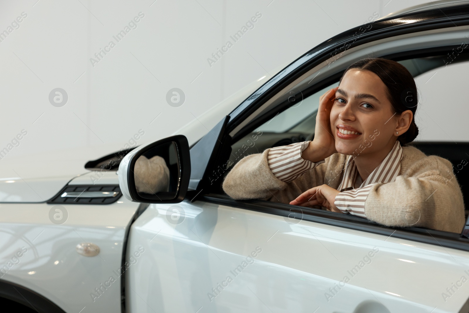 Photo of Happy woman inside new white car in salon