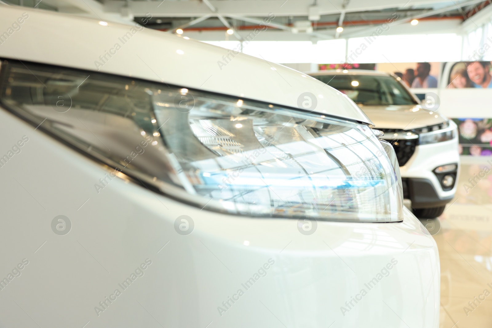 Photo of New modern white car in salon, closeup of headlight