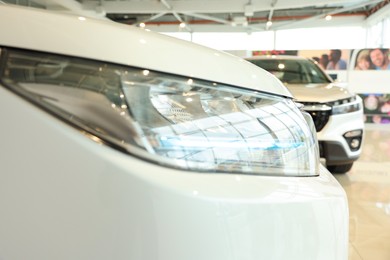 New modern white car in salon, closeup of headlight