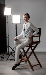 Photo of Beautiful woman with script sitting in director's chair in studio