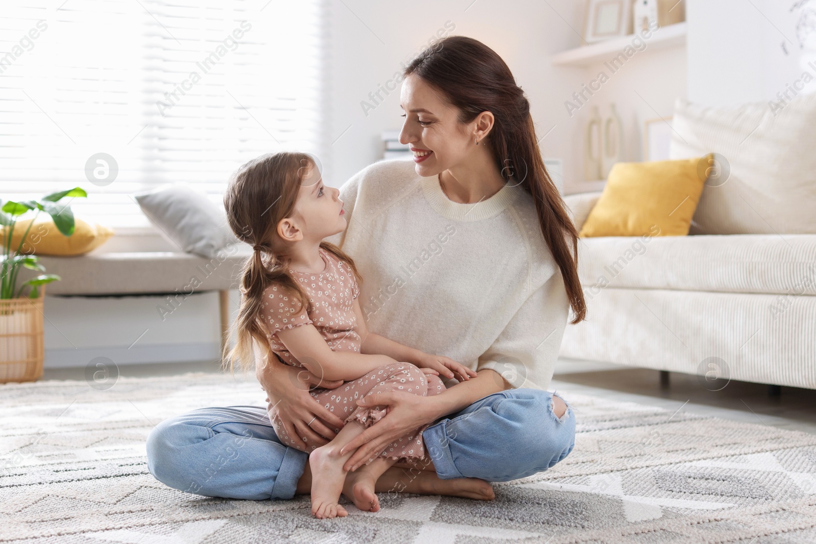 Photo of Happy mother with her cute little daughter on carpet at home