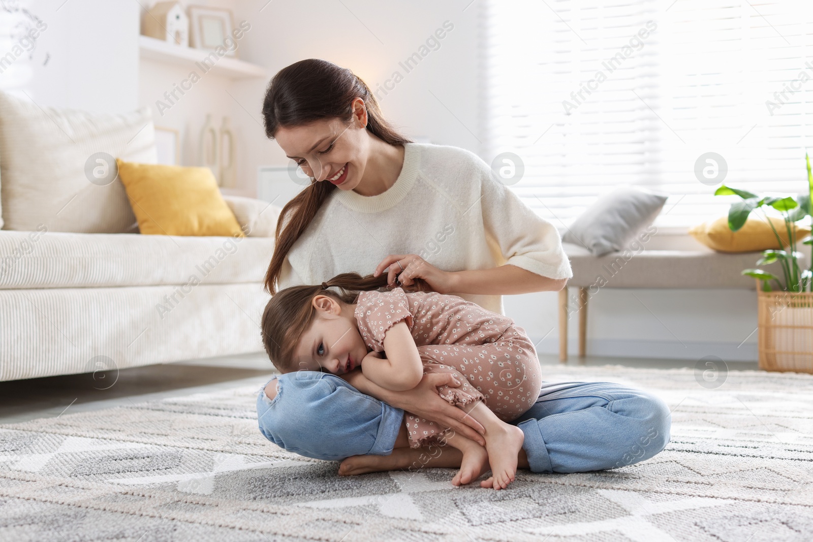 Photo of Happy mother with her cute little daughter on carpet at home