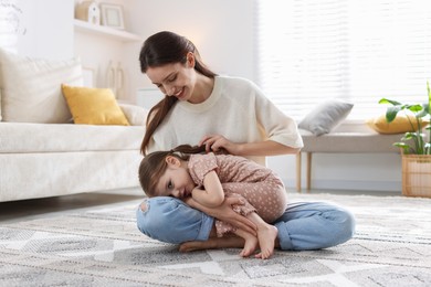 Happy mother with her cute little daughter on carpet at home