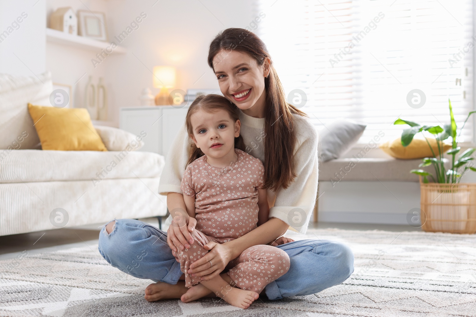 Photo of Happy mother with her cute little daughter on carpet at home