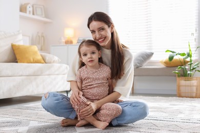 Happy mother with her cute little daughter on carpet at home