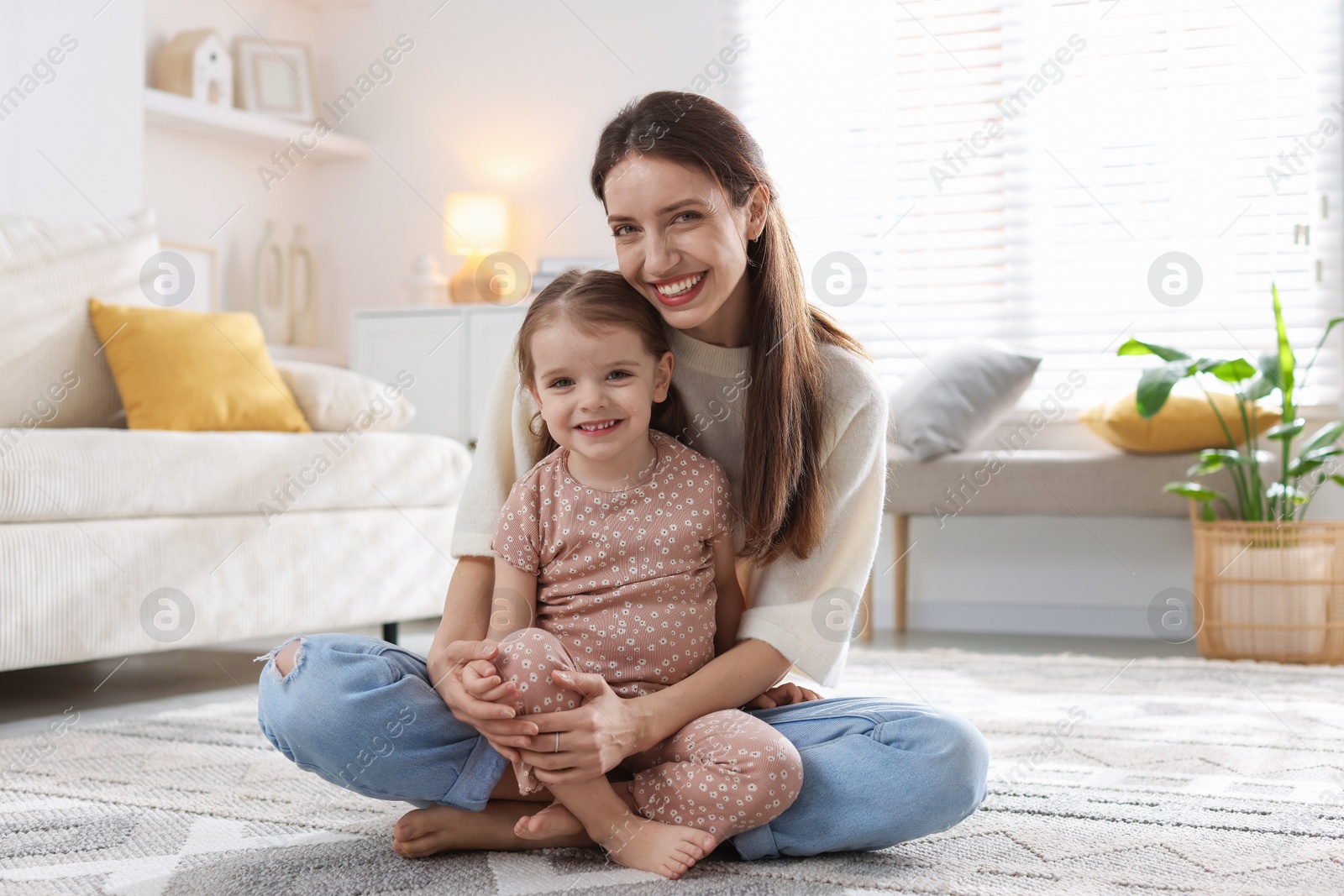 Photo of Happy mother with her cute little daughter on carpet at home