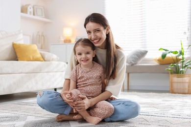 Happy mother with her cute little daughter on carpet at home