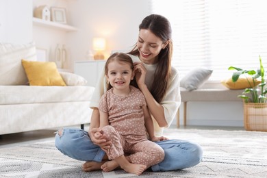 Happy mother with her cute little daughter on carpet at home