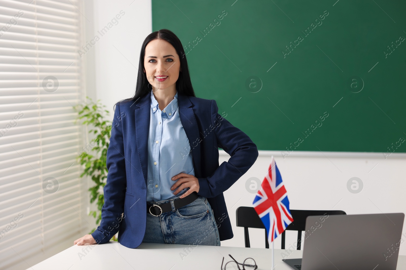 Photo of English teacher at desk in classroom. Space for text