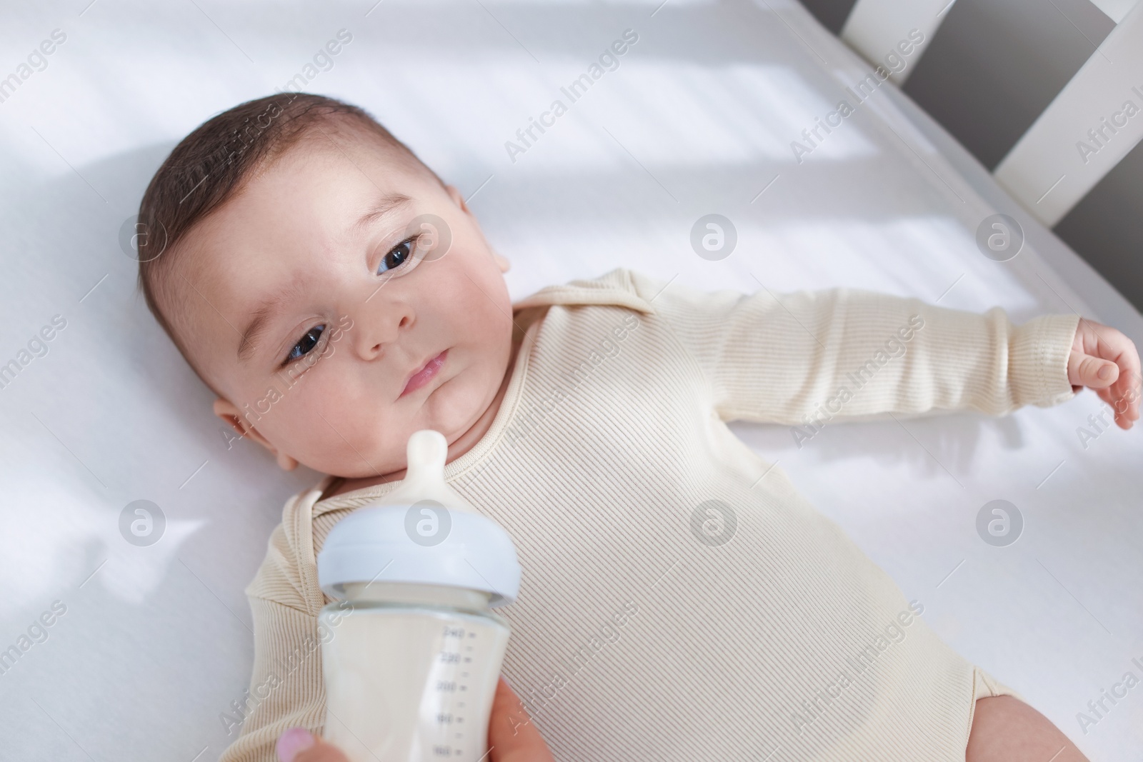 Photo of Mother feeding her little baby from bottle indoors, top view