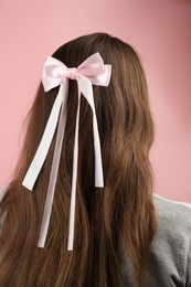 Woman with stylish hair bow on pink background, back view