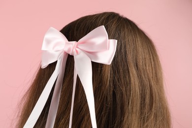 Woman with stylish hair bow on pink background, closeup