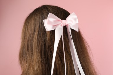 Photo of Woman with stylish hair bow on pink background, closeup